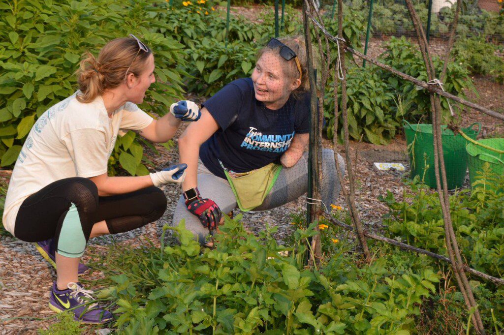 Two students work together at a community garden.